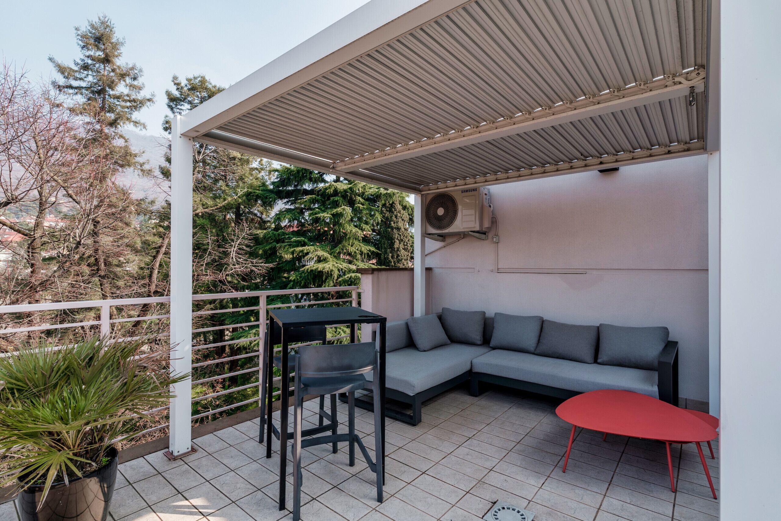A covered outdoor seating area with a sofa, a table, and chairs.