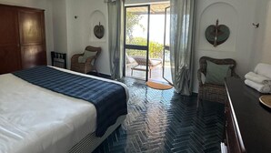 Ein Hotelzimmer mit Bett, Schreibtisch, Stuhl, kleinem Tisch und Blick ins Freie.