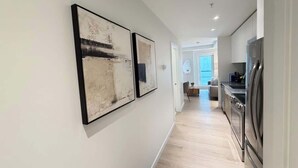 Une cuisine moderne dotée d’appareils électroménagers en acier inoxydable, d’un plancher en bois et d’un couloir agrémenté de deux œuvres d’art encadrées.
