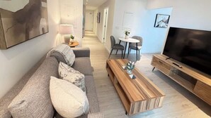 Un salon moderne comprenant un canapé, une table basse, un téléviseur et un coin repas avec des chaises et une table.