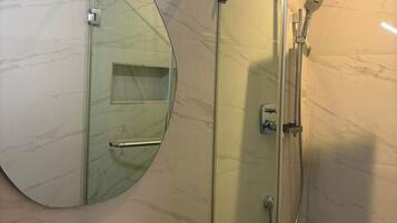 A bathroom with a glass-enclosed shower, a sink, and a large mirror.