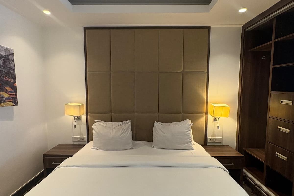 Een hotelkamer met een groot bed, twee bedlampen, een hoofdeinde en een kledingkast.