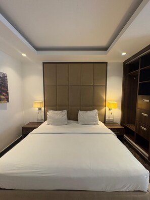 Een hotelkamer met een groot bed, twee bedlampen, een hoofdeinde en een kledingkast.