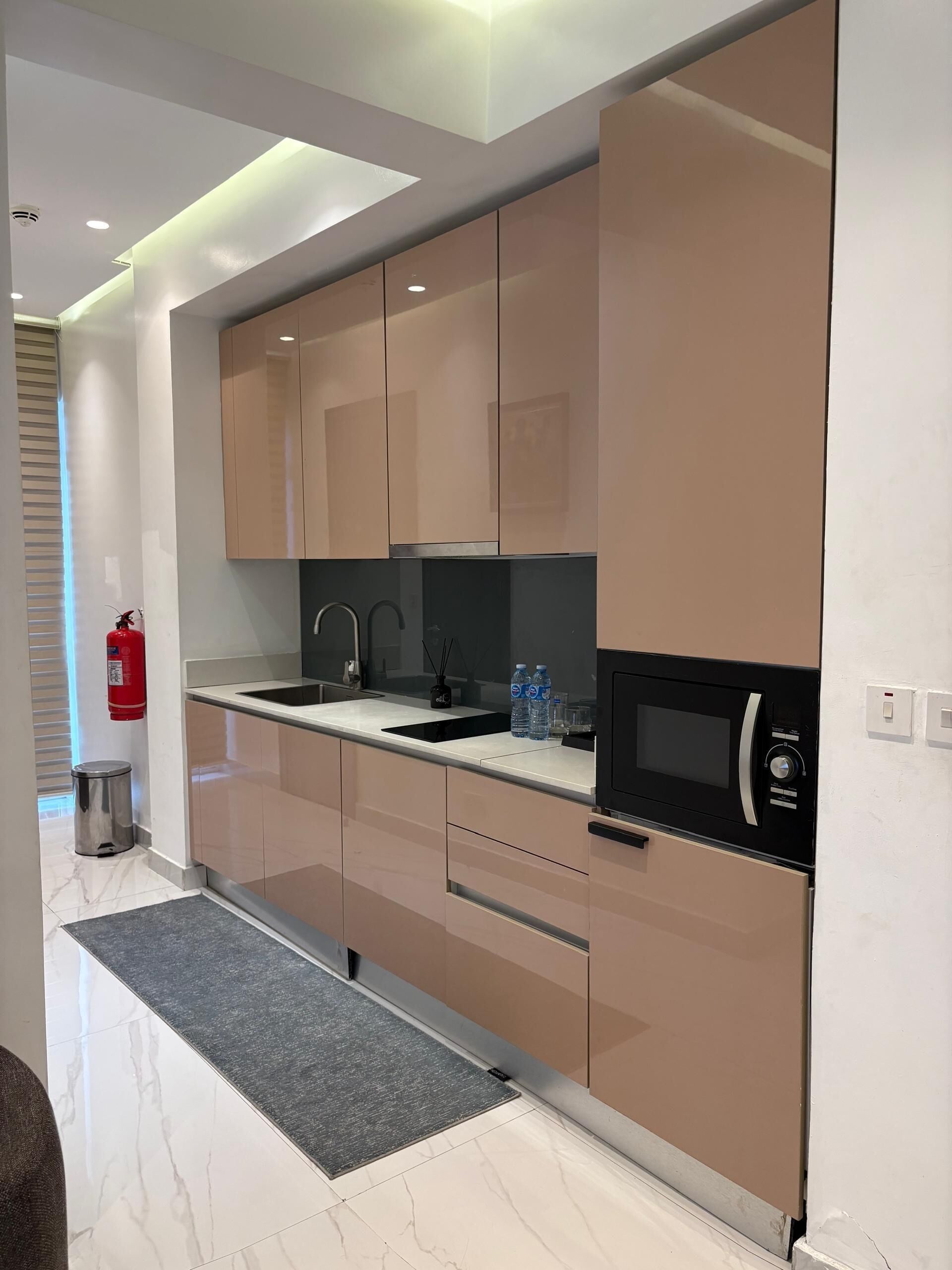 A modern kitchen with sleek cabinetry, a black microwave, and a stainless steel sink.