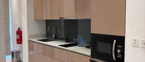 A modern kitchen with sleek cabinetry, a black microwave, and a stainless steel sink.