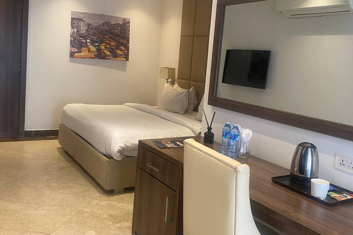 Een hotelkamer met een bed, een bureau, een stoel, een televisie en een schilderij aan de muur.