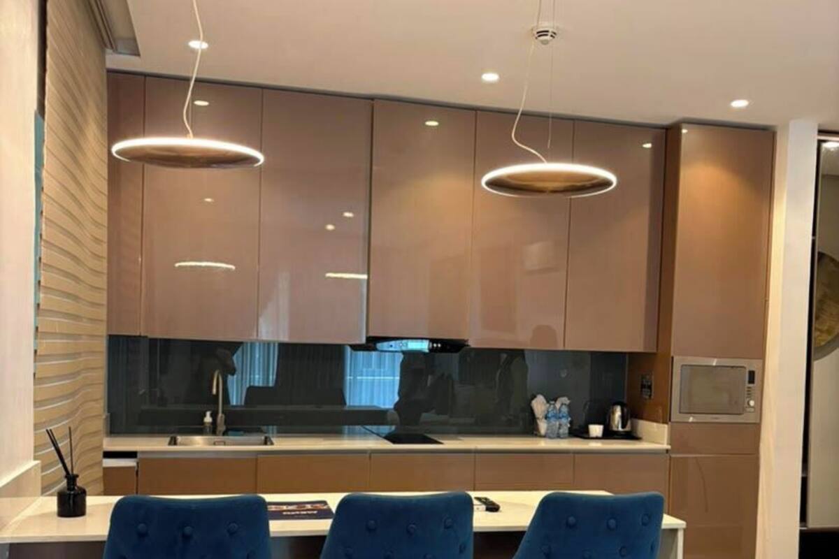 Een moderne keuken met een centraal eiland, barstoelen en hanglampen.