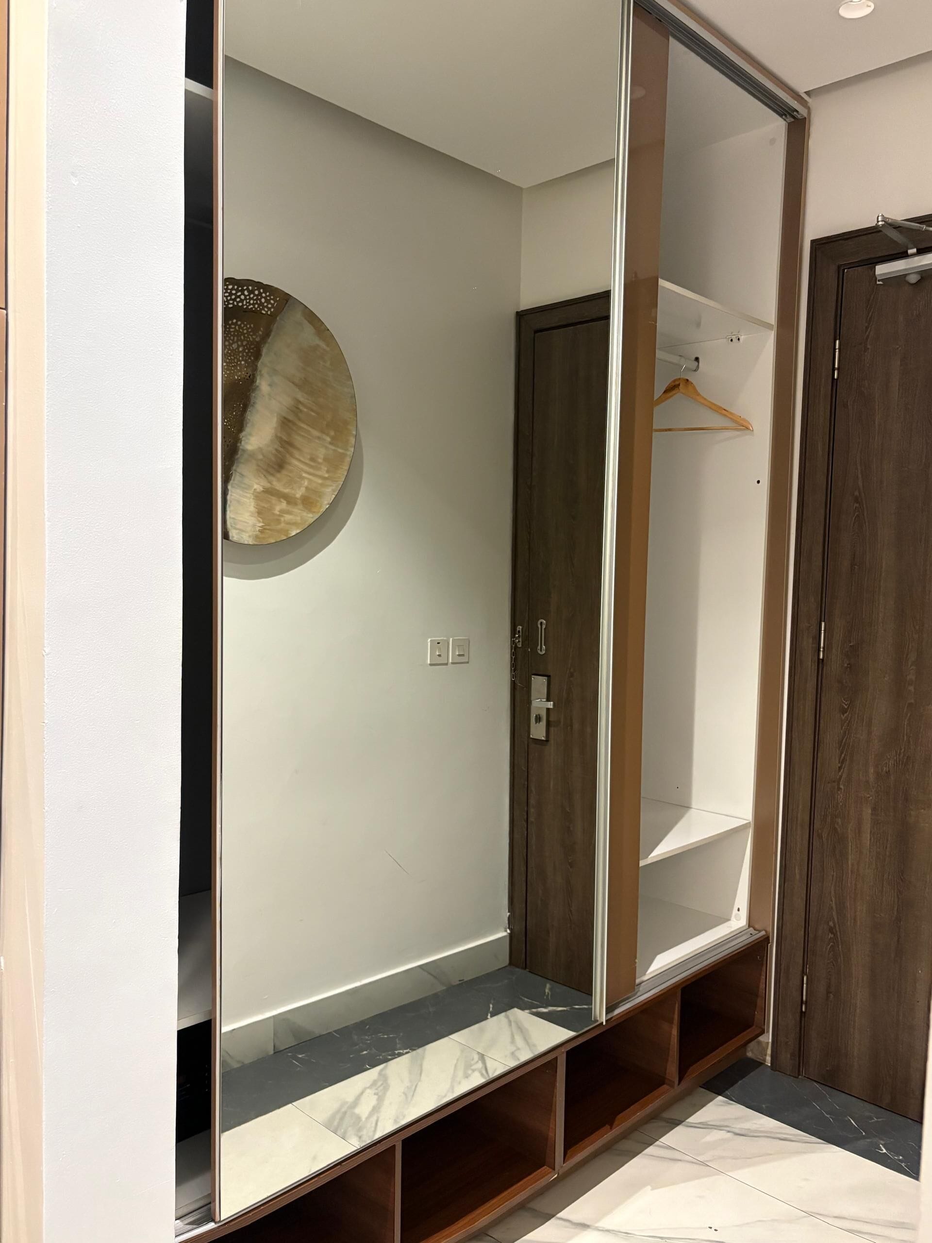 A walk-in closet with a wooden door, a hanging rod, and a marble-tiled floor.