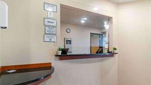 A reception area with a reception desk, a clock, and a sign indicating office hours and check-in/check-out times.