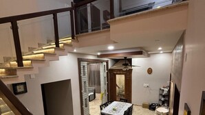 A multi-level interior with a staircase, a dining area with a table and chairs, and a kitchen area with a sink. - Sadachandra Home Stay (Kundapur)