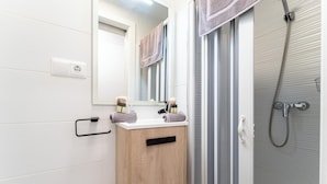 Une salle de bain moderne avec un meuble-lavabo en bois, un miroir et un espace douche.