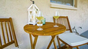 A round wooden table with two chairs, a white lantern, and two glasses of white wine. - Steps 2 Sand | Magical Sunsets | Carefree Checkout (Indian Rocks Beach)