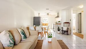 A modern living room with a beige sofa, a wooden coffee table, and a dining area with a table and chairs. - Steps 2 Sand | Magical Sunsets | Carefree Checkout (Indian Rocks Beach)