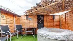 Una terraza de madera con un área de descanso cubierta, una mesa y sillas.