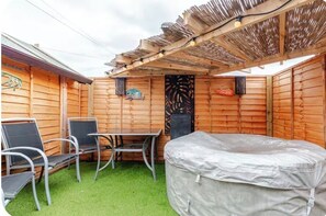 A wooden deck with a covered seating area, a table, and chairs. - modern luxury cottage (Ayr)