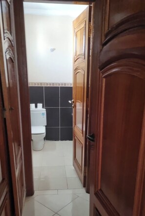 A narrow hallway leading to a bathroom with a toilet and a tiled wall. - Luxurious Accessible Apartment in the Heart of Fes (Fes)