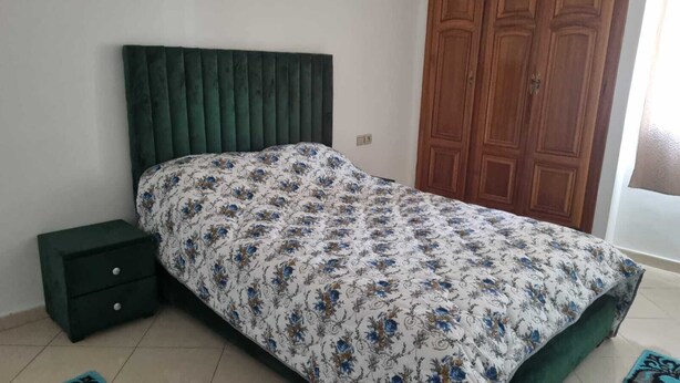 Un dormitorio con una cama, una mesita de noche y una puerta de madera.