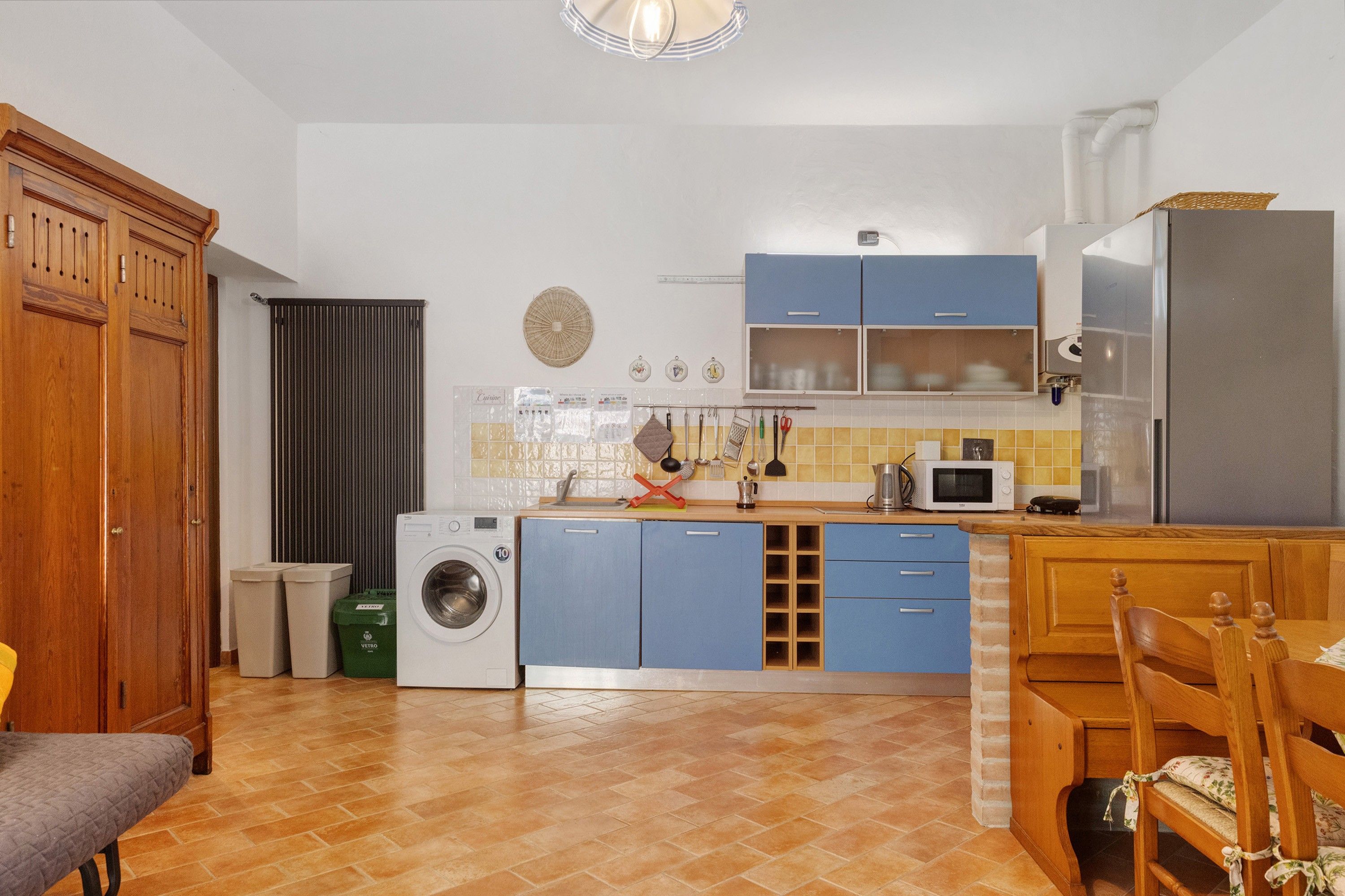 A compact kitchen with a washing machine, a microwave, and blue cabinets.