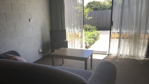 A living room with a sofa, a table, and a TV. - City Central Motor Inn And Apartments (Warrnambool)