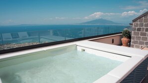A rooftop infinity pool with clear blue water, a glass balustrade, and a view of the ocean and a mountain in the distance. - Borgo Mezzo Monte. Panoramic Sea View,Jacuzzi and Concierge by Feeling Italy (Sorrento)