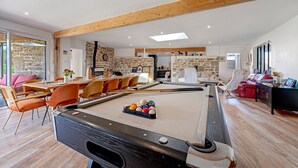 A pool table in a spacious room with a dining area, stone walls, and wooden beams. - Kerlonie Family Haven: Spacious Holiday Home with Private Terrace, Wi-Fi & Air Conditioning (Kerlouan)
