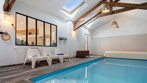 An indoor swimming pool with a skylight, wooden beams, and white walls. - Kerlonie Family Haven: Spacious Holiday Home with Private Terrace, Wi-Fi & Air Conditioning (Kerlouan)