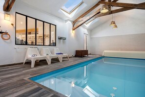 Ein Hallenbad mit Oberlichter, Holzbalken und weißen Wänden.