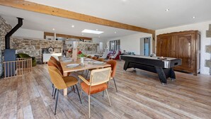 A spacious living area with a dining table, chairs, a pool table, and a stone wall. - Kerlonie Family Haven: Spacious Holiday Home with Private Terrace, Wi-Fi & Air Conditioning (Kerlouan)