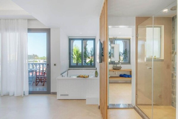 A modern interior with a kitchen area, a glass shower enclosure, and a view of the outdoors. - Drossia Hotel (Hersonissos)