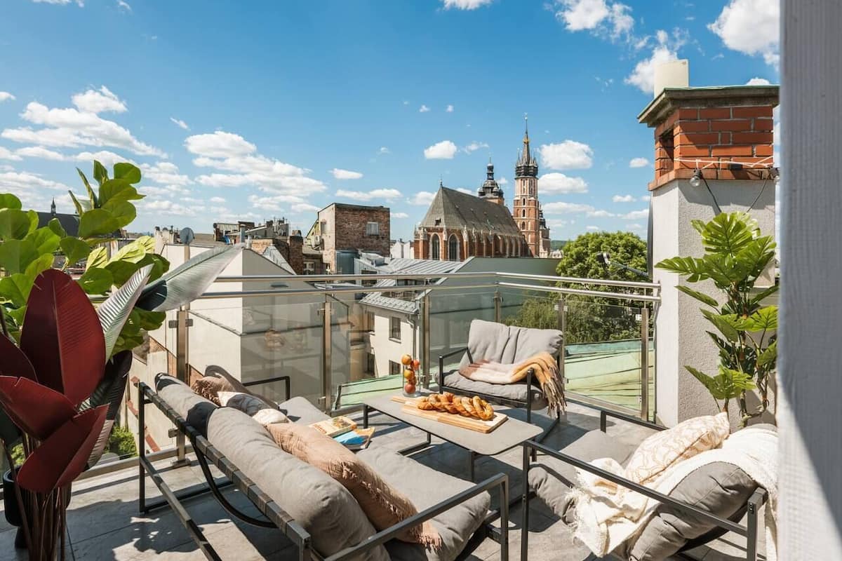 Terraza en la azotea con mobiliario exterior, vista a un edificio histórico y cielo despejado.