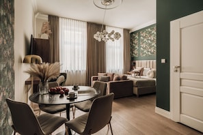 Uma sala de estar moderna com uma mesa de jantar redonda, dois sofás e uma janela grande com cortinas leves.