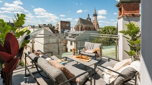 A rooftop terrace with a glass balustrade, outdoor seating, and a view of a historic church. - White Lotus by Fragola Collection (Kraków)