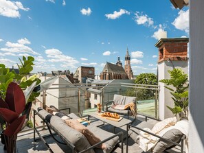 A rooftop terrace with a glass balustrade, outdoor seating, and a view of a historic church. - White Lotus by Fragola Collection (Kraków)