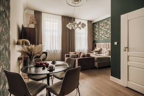 A modern living room with a sofa, a dining table with chairs, and a large window with curtains. - White Lotus by Fragola Collection (Kraków)