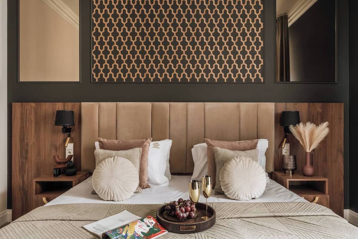 Un dormitorio con una cama grande, dos mesitas de noche, un cabecero y un panel decorativo sobre la cama.