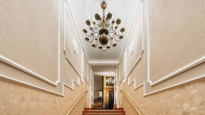 A grand staircase with marble walls and a chandelier. - White Lotus by Fragola Collection (Kraków)