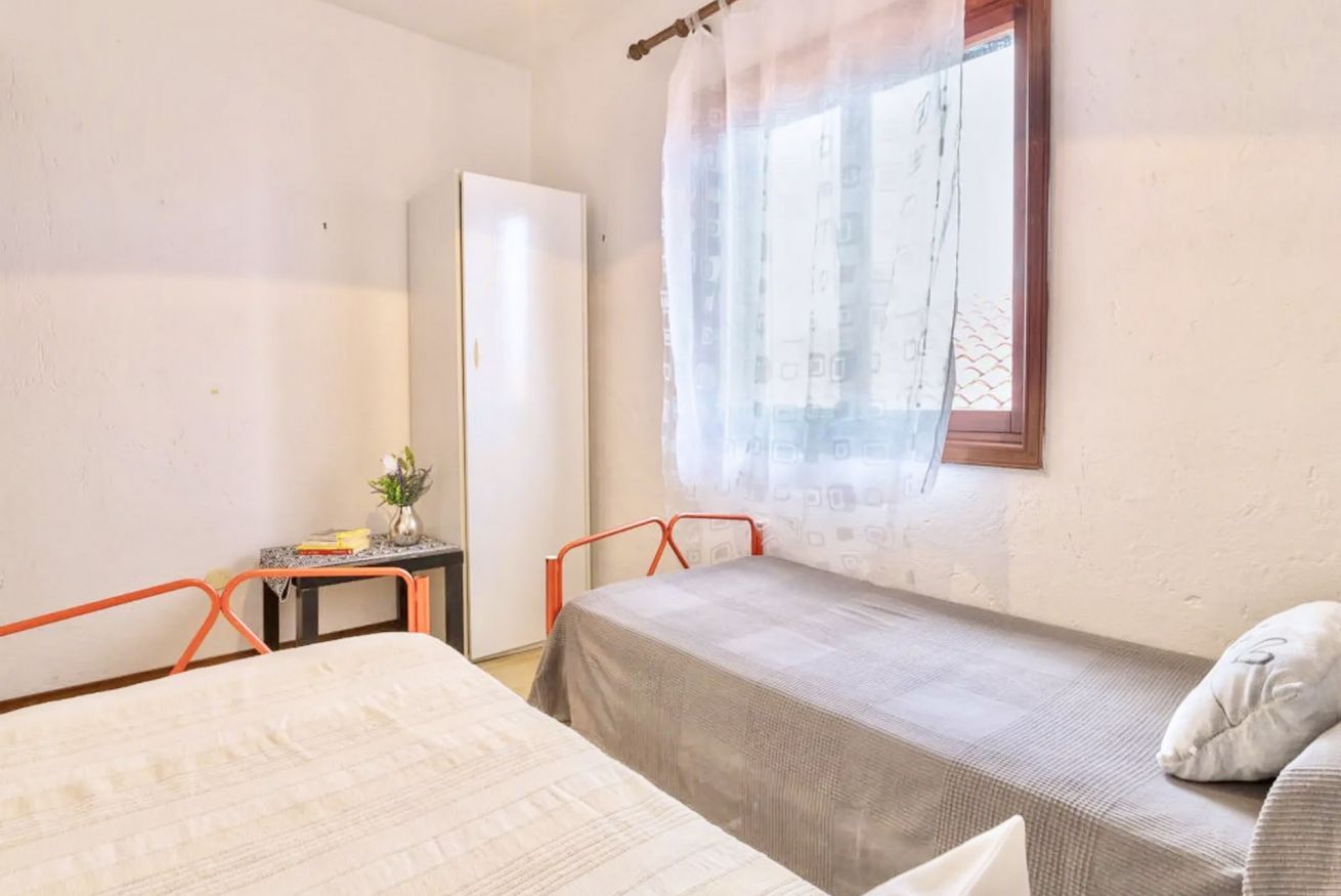Un alojamiento pequeño, con una habitación individual, dos camas, un escritorio y una ventana con cortina.