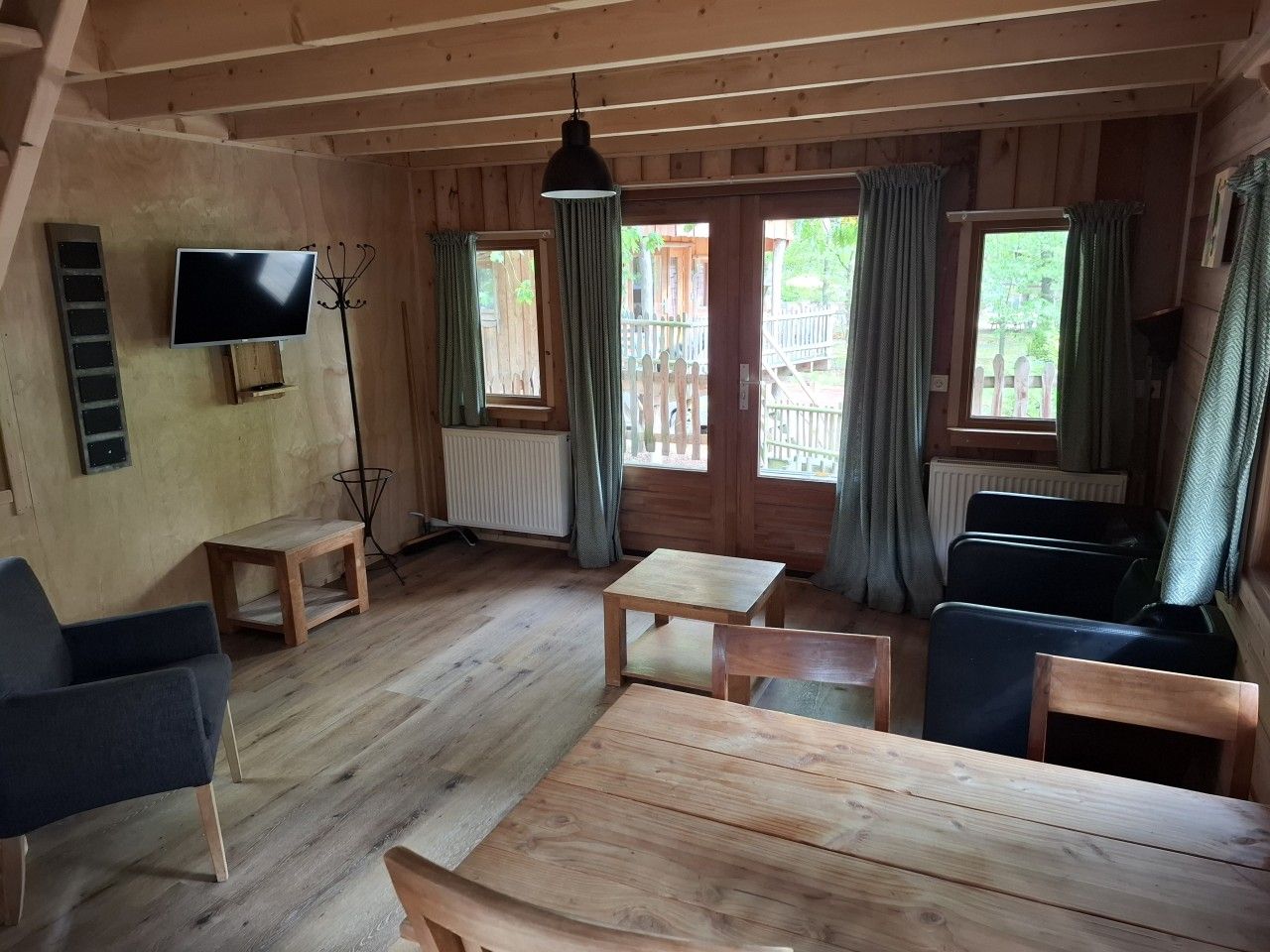 Ein Holzblock-Innenraum mit Fernseher, Sitzgelegenheiten und Blick ins Freie.