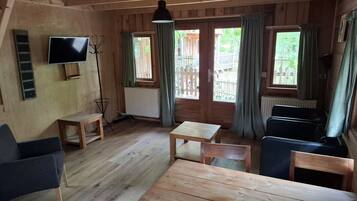 Ein Holzblock-Innenraum mit Fernseher, Sitzgelegenheiten und Blick ins Freie.
