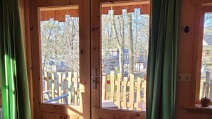 A wooden cabin with a large sliding door, a wooden deck outside, and a doormat on the floor.