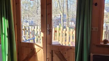 Een houten vakantiehuis met een grote schuifdeur, een houten terras buiten en een deurmat op de vloer.