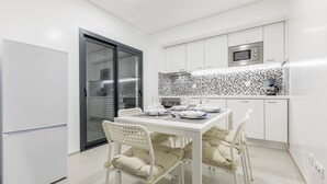 A modern kitchen with white cabinetry, a microwave, and a tiled backsplash. - Correeira Luxury Residence E (Albufeira)