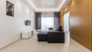 A modern living room with a sectional sofa, a flat-screen TV, and a wooden accent wall. - Correeira Luxury Residence E (Albufeira)