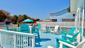 Una terraza con sillas, una mesa, una piscina y una valla blanca.