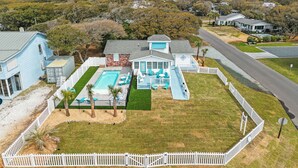 Propiedad residencial con piscina, patio cercado y una carretera al fondo.