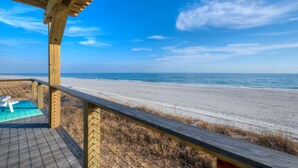 Une terrasse en bois offrant une vue sur la plage et l’océan.