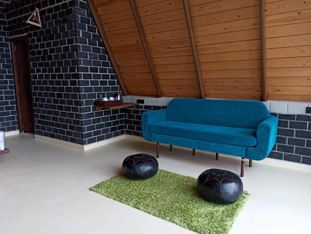 Ein Zimmer mit einem blauen Sofa, schwarzen Ziegelwänden und einer Holzbalkendecke.