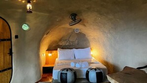 A cozy, circular room with a bed centered in the space, a wooden bench, and a small table. - The Cloud Resort (Kadugannawa)