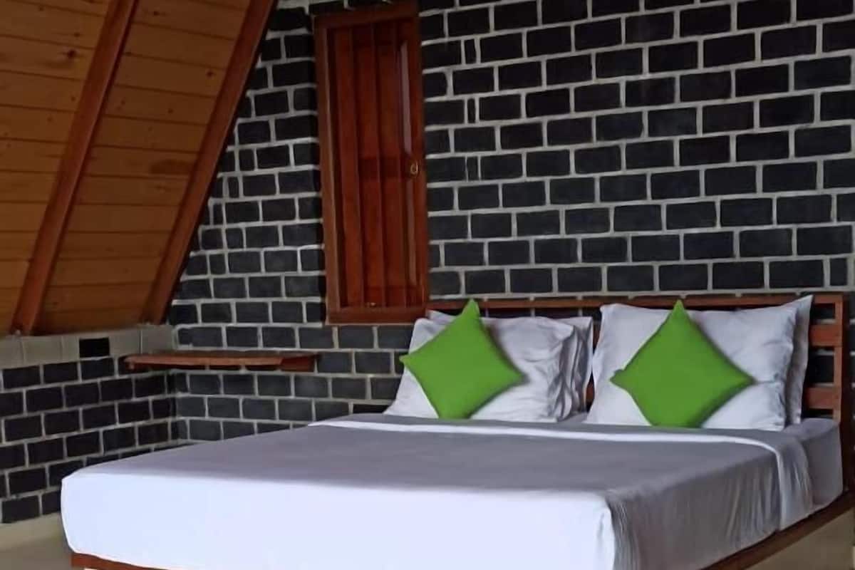 A bedroom with a bed, wooden headboard, and a brick wall.