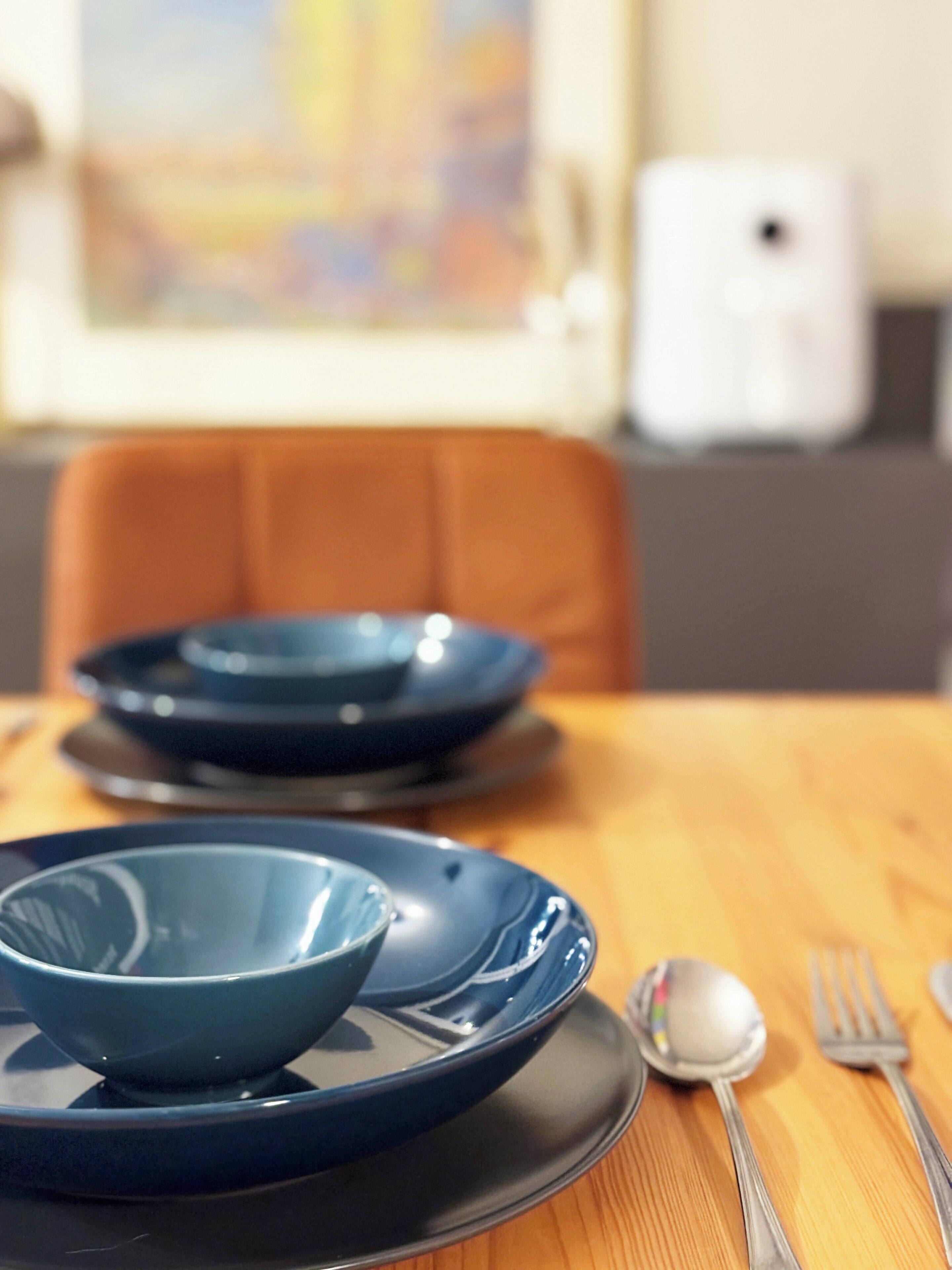 Una mesa de comedor con platos azules, una cuchara y un tenedor.